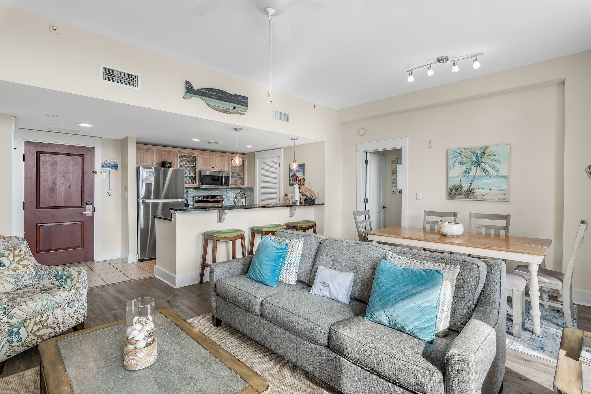 A modern living room with a grey sofa, a coffee table, and a dining area with a wooden table and chairs.