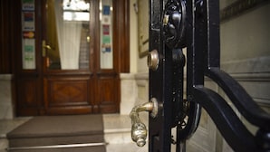 Una puerta con picaporte de latón y cerradura, que da a una escalera con rellano alfombrado.