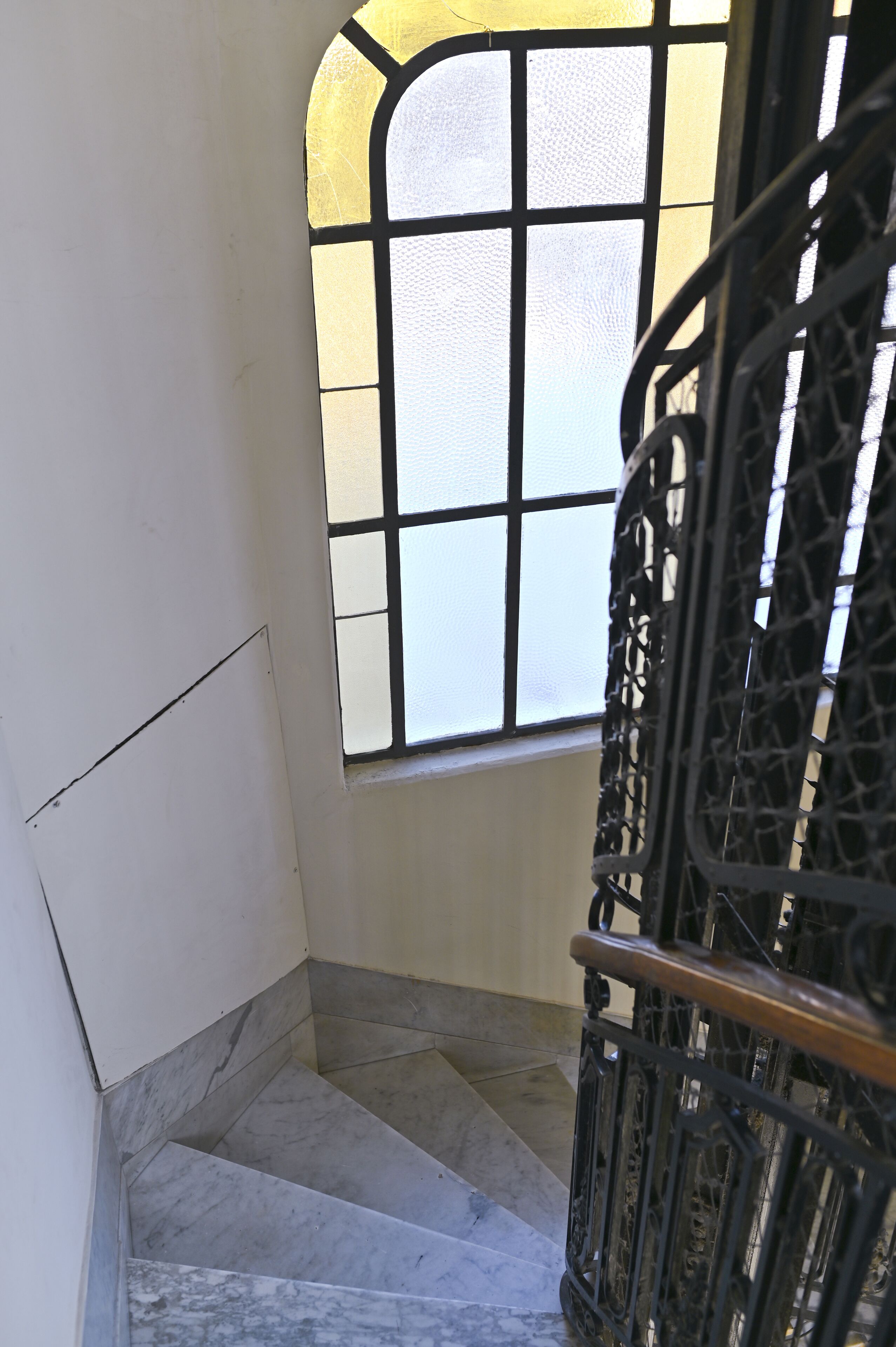 A staircase with marble steps leading to a room with a window.