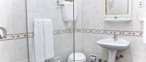 A bathroom with a toilet, bidet, and sink, all with white fixtures.