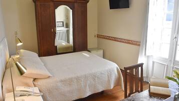 A bedroom with a bed, bedside lamp, telephone, and a wooden wardrobe.