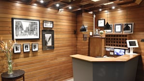 Un área de recepción con paneles de madera, cuadros enmarcados, un mostrador de recepción e iluminación colgante.