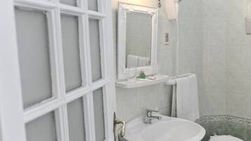 Un baño con lavamanos blanco, espejo, secador de pelo y inodoro.