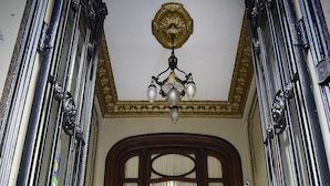 Una entrada imponente con puerta de madera, escalones y una araña.