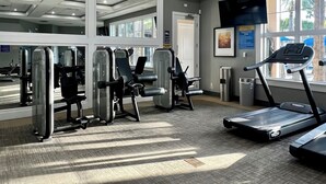 A gym with exercise equipment, a treadmill, and large windows.