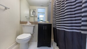 A bathroom with a toilet, a cabinet, a mirror, and a shower curtain. - 521 Studio Hollywood Beach (Hollywood)
