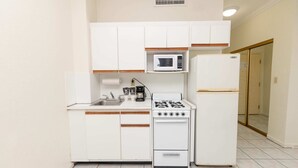 A compact kitchen with white cabinets, a microwave, a stove, and a refrigerator. - 521 Studio Hollywood Beach (Hollywood)