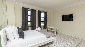 A bedroom with a bed, a TV mounted on the wall, and a small table with chairs. - 521 Studio Hollywood Beach (Hollywood)