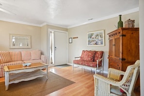 A living room with a striped sofa, a red armchair, a wooden cabinet, and a wicker chair.