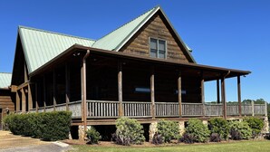 A log cabin with a porch, a metal roof, and a stone foundation. - Lodge on The Lake (Rutledge)