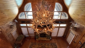 A high-ceilinged room with wooden walls and a chandelier made of antlers. - Lodge on The Lake (Rutledge)