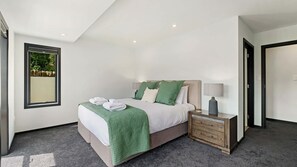 Une chambre moderne avec un lit, une table de chevet et une vue sur la verdure.