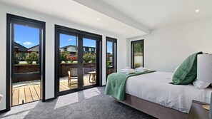 Un dormitorio con cama, una manta verde y vistas a una terraza.