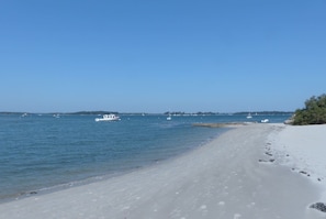 Une plage avec une eau d’un bleu limpide, des bateaux et un rivage sablonneux.