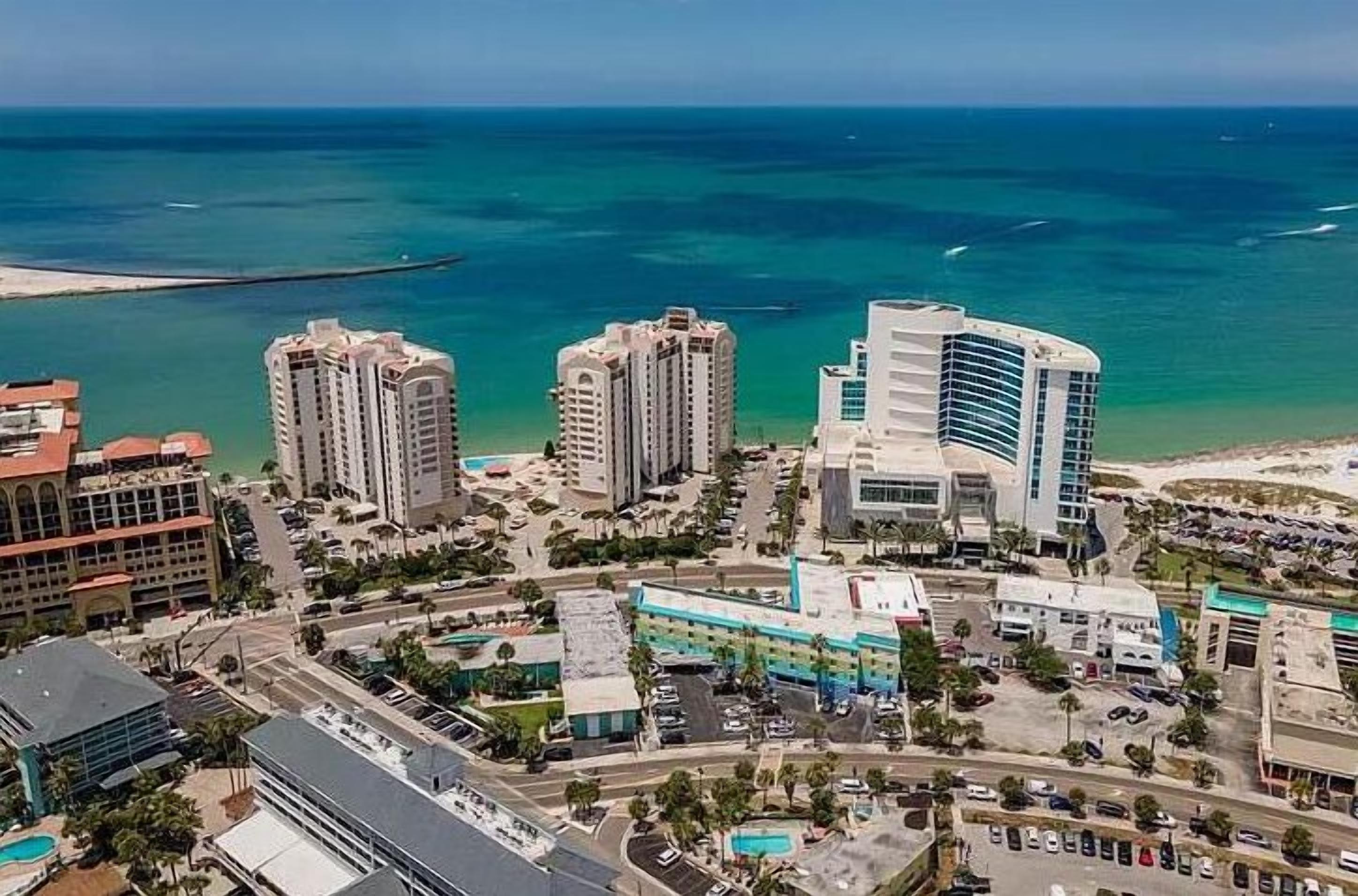 A coastal cityscape with high-rise buildings, a marina, and a beach.