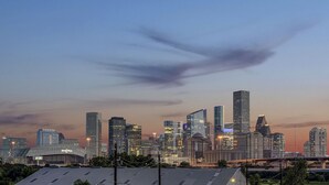 Une vue sur les toits d’une ville, avec des immeubles modernes et des gratte-ciel, et un pont au premier plan.