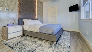 Une chambre à coucher moderne avec un lit, une table de chevet et un téléviseur encastré.