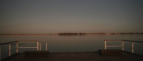 A calm waterfront deck with two benches and a railing.