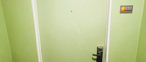 A green door with a no smoking sign, a doorbell, and a small window.