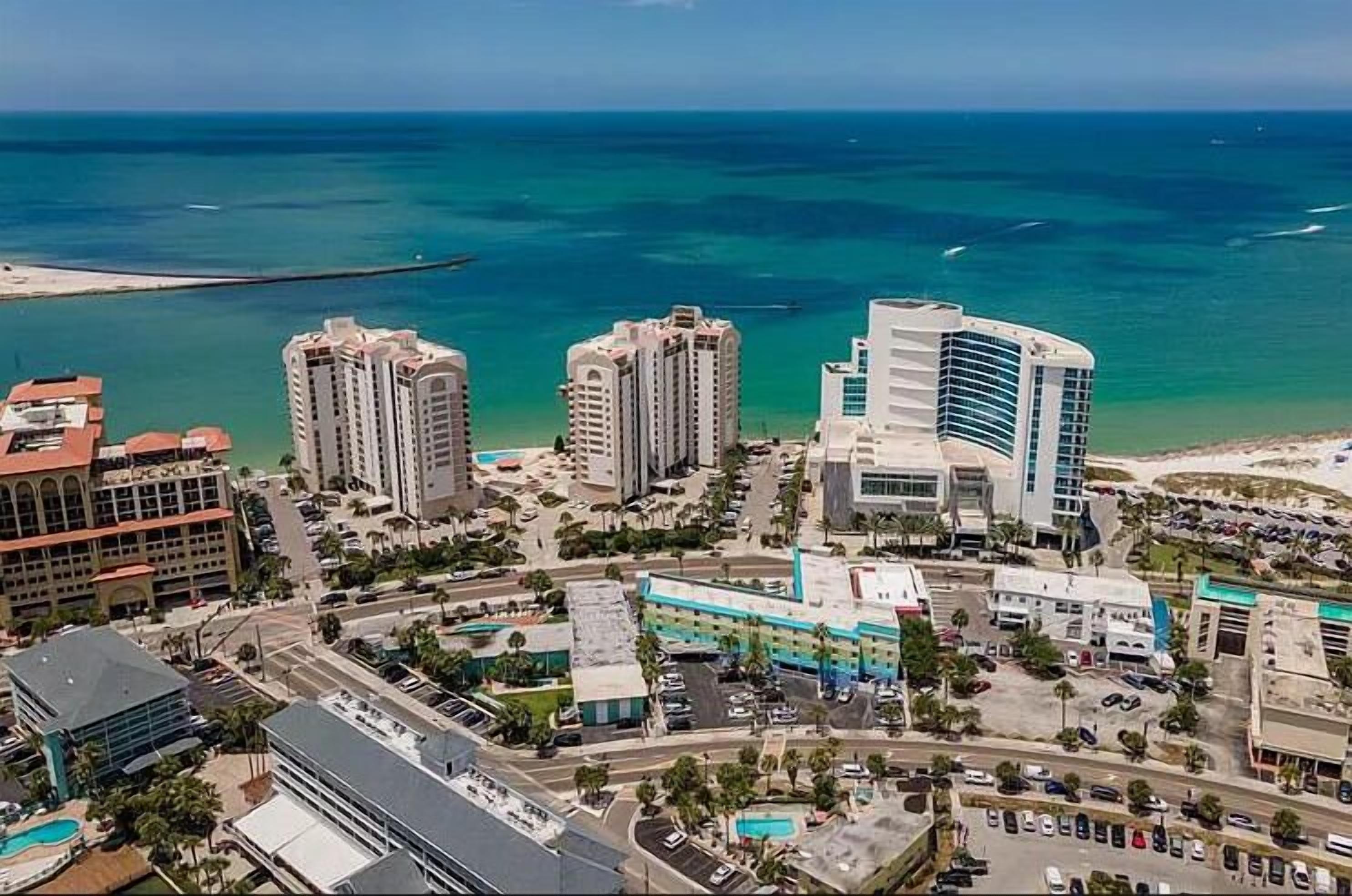 An aerial view of a coastal city with high-rise buildings, a marina, and a beach.