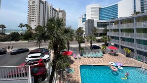 A hotel with a pool area, including lounge chairs and umbrellas, and a view of the ocean.