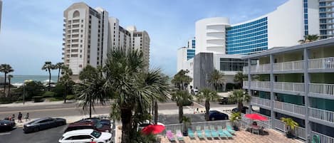 Un hotel con zona de piscina, que incluye sillones y sombrillas, y vistas al océano.