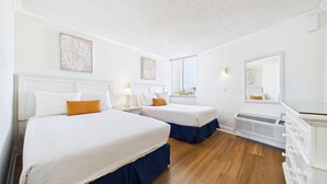 Habitación de hotel con dos camas, una ventana con persianas, un espejo y un radiador.