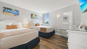 Hotelkamer met twee bedden, een groot raam, een flatscreen-tv en een bureau met een spiegel.