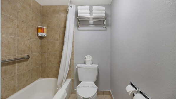 A bathroom with a bathtub, toilet, and a towel rack.