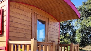 A wooden cabin with a curved roof, a small porch, and a window.
