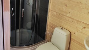 A compact bathroom with a glass-enclosed shower, a toilet, and a window.