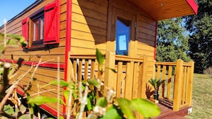 A wooden cabin with a porch, a window, and a door.