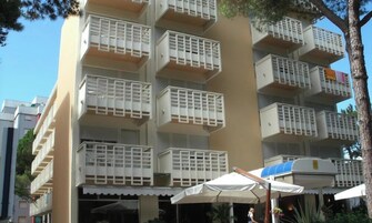 Un edificio a più piani con balconi, posti a sedere all'aperto e un albero.