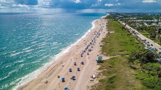 An aerial view of a beach with rows of umbrellas and beachgoers. - Ocean Pearl 2 Blocks to A1A-Delray Beach! (Delray Beach)