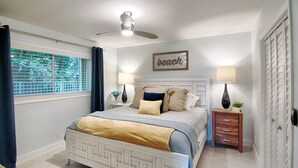 A bedroom with a bed, a ceiling fan, a window with curtains, a bedside table with a lamp, and a wall with a framed sign. - Ocean Pearl 2 Blocks to A1A-Delray Beach! (Delray Beach)