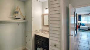 A bathroom with a white vanity, dark drawers, a small shelf with a sailboat decoration, and a mirror above the sink. - Ocean Pearl 2 Blocks to A1A-Delray Beach! (Delray Beach)