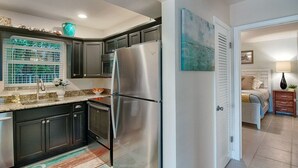 A modern kitchen with dark cabinets, stainless steel appliances, and a window with a view. - Ocean Pearl 2 Blocks to A1A-Delray Beach! (Delray Beach)