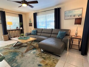 A living room with a sectional sofa, a coffee table, a floor lamp, a side table, and a ceiling fan. - Ocean Pearl 2 Blocks to A1A-Delray Beach! (Delray Beach)