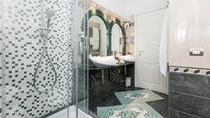 A modern bathroom with a glass-enclosed shower, a sink with a mirror above, and a tiled floor. - Superior Suite (St. Peter Vatican Bambino Gesù Gianicolo) (ROMA)