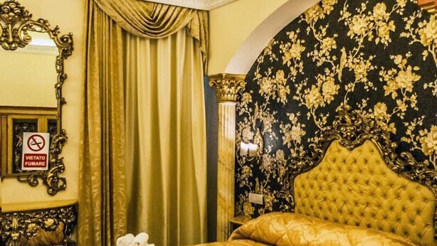 A luxurious bedroom with a large bed, ornate ceiling, and floral wallpaper. - Executive Suite room (Roma)
