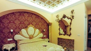A luxurious bedroom with a large bed, ornate headboard, and a decorative ceiling. - Presidential Suite (Roma)