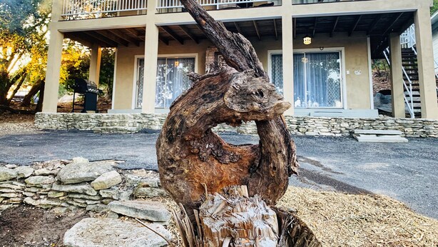 Un edificio con un balcón y una gran escultura de madera en la fachada.