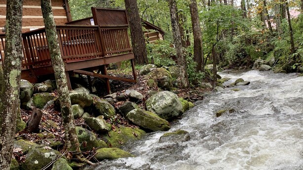 A wooden cabin with a deck overlooking a fast-flowing river, surrounded by dense forest. - Foot of the Smokies, quiet wooded paradise. Gatlinburg Pigeon Forge (Cosby)