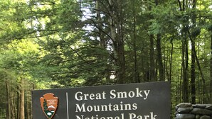 A sign for Great Smoky Mountains National Park with a stone wall and forest in the background. - Foot of the Smokies, quiet wooded paradise. Gatlinburg Pigeon Forge (Cosby)