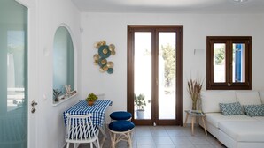 Ein helles Wohnzimmer mit einem weißen Sofa, einem blau-weißen karierten Tisch und einem großen Fenster.