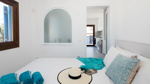 Ein Schlafzimmer mit Bett, Fenster, Spiegel und Blick ins Freie.