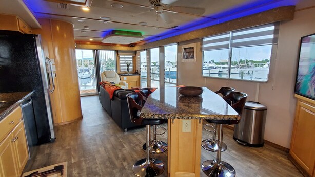A modern kitchen with a bar area, large windows, and a view of the marina. - Key West Luxury Houseboat (Key West)