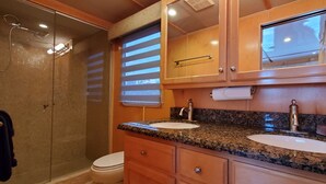 A bathroom with two sinks, a shower, and wooden cabinets. - Key West Luxury Houseboat (Key West)