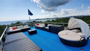 A deck with outdoor seating, a flag, and a view of the sea. - Key West Luxury Houseboat (Key West)