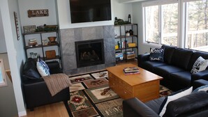A living room with a fireplace, a flat-screen TV, a sofa, a coffee table, and a bookshelf.